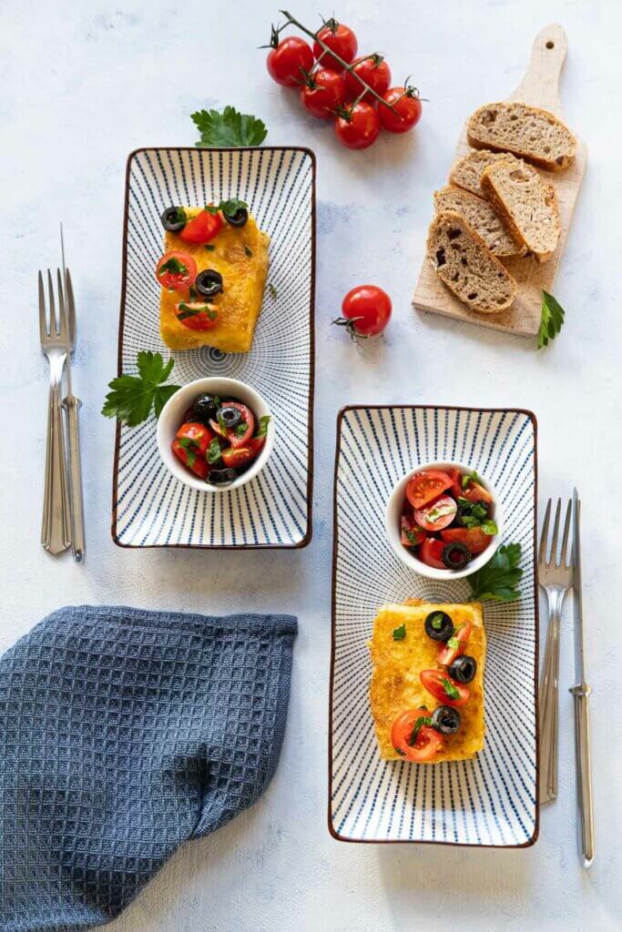 Gebratener Feta mit Tomaten und Oliven auf einem Teller