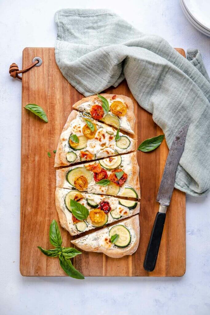 Flatbread mit doppelt gerösteten Tomaten, Zucchini und Ricotta geschnitten